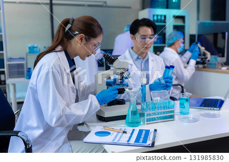 Team of biochemical research scientists working with a microscope for vaccine development 131985830