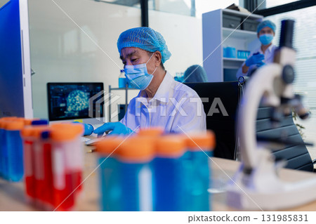 Team of biochemical research scientists working with a microscope for vaccine development 131985831