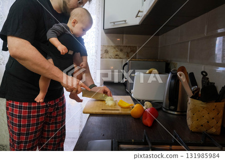 Father Cooking with Baby in Carrier 131985984
