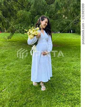 Pregnant Woman Holding Flowers in Park Pregnant Woman Holding Flowers in Park 131985999