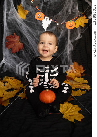 Baby in Skeleton Costume with Pumpkin and Leaves Baby in Skeleton Costume with Pumpkin and Leaves 131986018