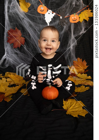 Baby in Skeleton Costume with Pumpkin and Leaves Baby in Skeleton Costume with Pumpkin and Leaves 131986024