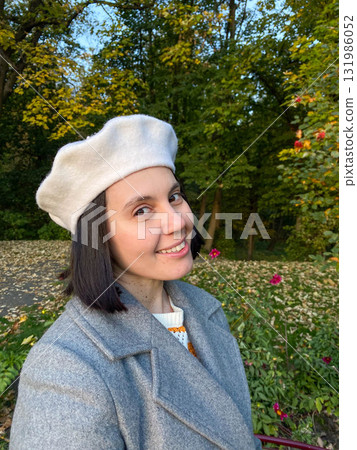 Woman in Gray Coat and Beret Smiling in Autumn Park 131986052