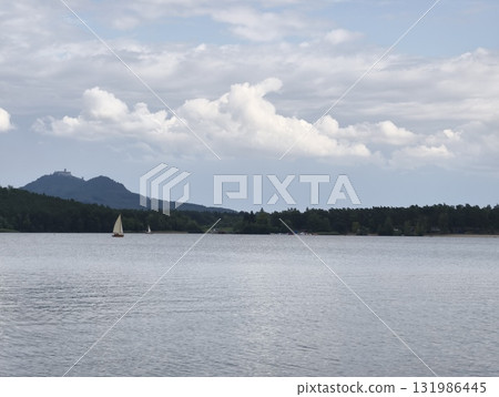 A serene lake scene with a sailboat and majestic mountains during a beautiful sunset 131986445