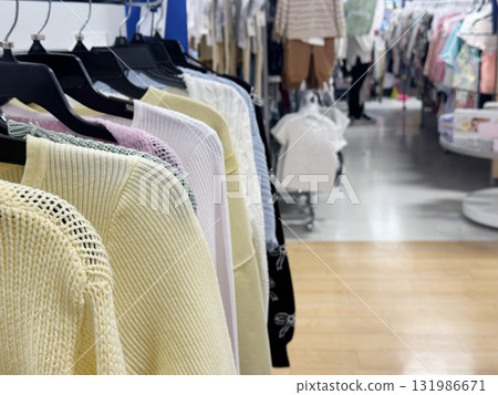 A store clothing rack displaying pastel sweaters and knit tops arranged neatly on hangers 131986671