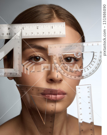 Creative portrait of woman with surgical markings and geometric rulers symbolizing symmetry and precision 131986890