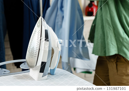 Ironing clothes in a well-lit laundry room for a fresh look and tidy appearance Ironing clothes in a well-lit laundry room for a fresh look and tidy appearance 131987101