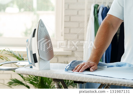Ironing clothes while preparing for a busy day at home in a bright room 131987131
