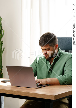 Man working diligently on laptop in modern office setting 131987134