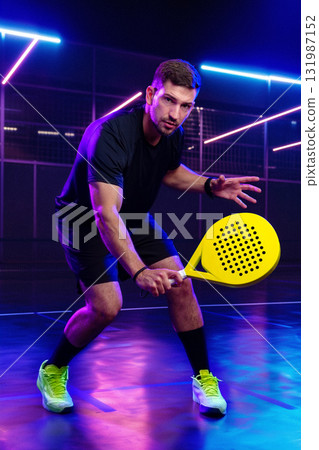 Padel player in action on a brightly lit court at night 131987152