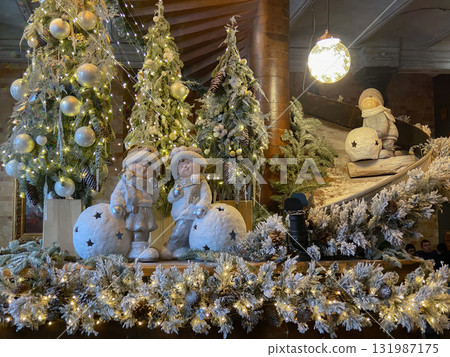 A festive and cosy indoor scene featuring a Christmas or Winter holiday display, likely within a hotel lobby A festive and cosy indoor scene featuring a Christmas or Winter holiday display, likely within a hotel lobby 131987175