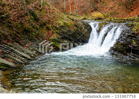 autumn scenery with waterfall. stones seen through transparent water. orange foliage on the hill. cascades of the river turychka in fall season. overcast weather. travel destination of transcarpathia autumn scenery with waterfall. stones seen through transparent water. orange foliage on the hill. cascades of the river turychka in fall season. overcast weather. travel destination of transcarpathia 131987758