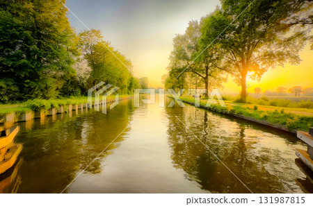 A Serene River Glowing at Sunrise Surrounded by Lush Greenery and Reflective Waters 131987815