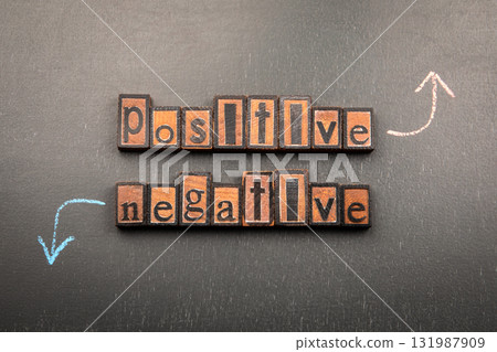 Positive and Negative with wooden letter blocks on blackboard and chalk arrows pointing up and down 131987909