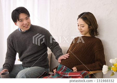 一對年輕夫婦在沙發上休息，孕婦 131988332