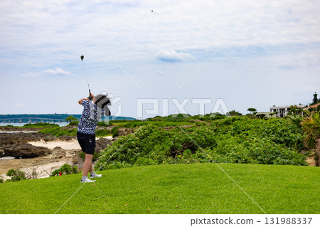 A golfer hitting a driver on a hole over the sea at a tropical resort golf course (Miyakojima City, Okinawa Prefecture) A golfer hitting a driver on a hole over the sea at a tropical resort golf course (Miyakojima City, Okinawa Prefecture) 131988337