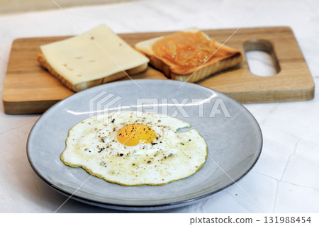 Breakfast served on the kitchen table with a fried egg on a plate and fresh bread and coffee Breakfast served on the kitchen table with a fried egg on a plate and fresh bread and coffee 131988454