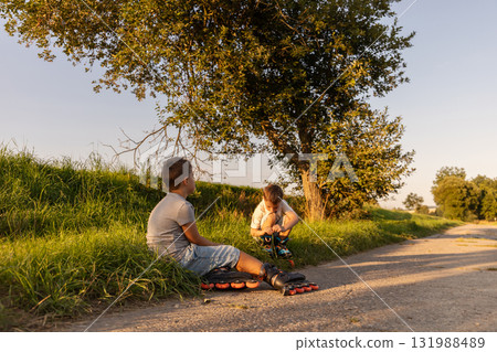 Children spend their free time inline skating on a path surrounded by greenery, sharing laughter and friendship under the warm sunlight 131988489