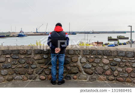 A man stands and looks at the ships in a port city by the sea. Bornholm Island, Denmark 131988491