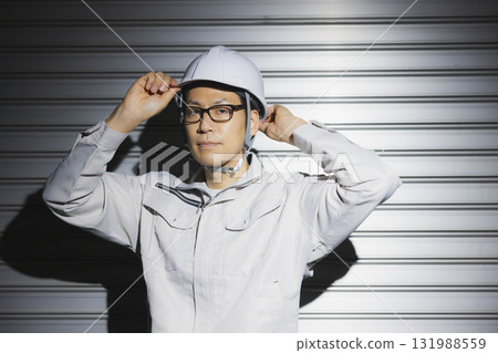 A man in work clothes wearing a helmet 131988559