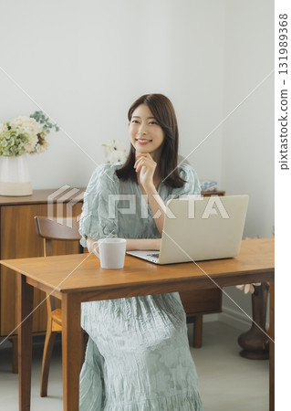 A woman watching a computer in a room 131989368