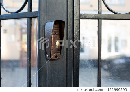 Doorbell installed on black metal gate, button clearly. Simplicity and functionality of design, perfect for topics related to home security, entrance systems and access control in residential areas 131990293