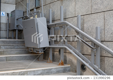 Elevator lift for people with disabilities at building stairs. Emphasizes accessibility with metallic design and functionality to ensure inclusivity in public spaces. Creating accessible environment 131990296