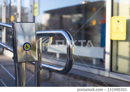 Close-up of accessibility button with wheelchair symbol on stainless steel handrail, designed to assist people with disabilities in entering public building or facility Close-up of accessibility button with wheelchair symbol on stainless steel handrail, designed to assist people with disabilities in entering public building or facility 131990301