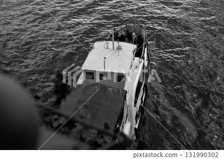 Black and white image of boat on water, passengers on board, capturing the serene motion of waterway, showcasing the transportation and leisure aspect of water travel 131990302