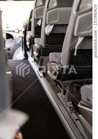 Inside the bus, the view shows empty seats lined up with a clear aisle. Sunlight brightens the space, indicating a daytime journey. The bus appears organized and clean 131990429
