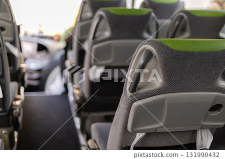 The interior of a bus shows rows of modern seats designed for comfort. Bright lighting enhances the welcoming atmosphere. Ideal for a relaxed journey through the city 131990432