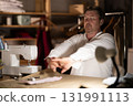 Sitting at workplace, man tailor does limbering-up, warms up numb muscles 131991113