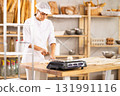 Female baker cutting dough with knife on kitchen table in bakery 131991116