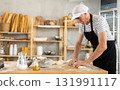 Experienced male baker kneads dough and shapes baguettes for baking in oven 131991117