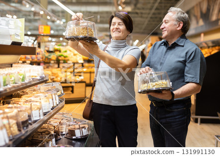 husband and wife choose cake in store for festive dinner 131991130