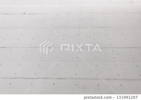 A close-up view of a concrete surface features evenly spaced holes. The setting suggests a construction area, illuminated by bright sunlight, highlighting the texture 131991207
