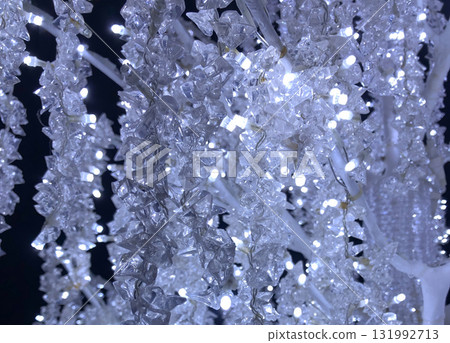 A mesmerizing, close-up vertical shot of crystal-like LED Christmas lights illuminated in a bright, cool white and icy blue glow against a deep black night sky. A mesmerizing, close-up vertical shot of crystal-like LED Christmas lights illuminated in a bright, cool white and icy blue glow against a deep black night sky. 131992713