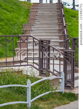 Granite staircase with wrought iron railings on green slope Granite staircase with wrought iron railings on green slope 131992731