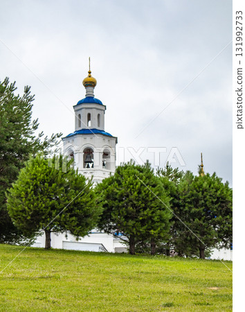 Orthodox bell tower behind pine trees golden dome and blue roof 131992733