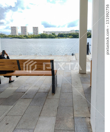 Bench on waterfront river view person sitting by the water Bench on waterfront river view person sitting by the water 131992756