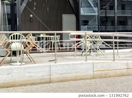 Empty summer cafe terrace with stacked chairs and metal railings Empty summer cafe terrace with stacked chairs and metal railings 131992762