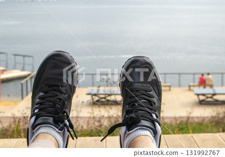 Black sneakers by the water POV on boardwalk horizontal composition Black sneakers by the water POV on boardwalk horizontal composition 131992767