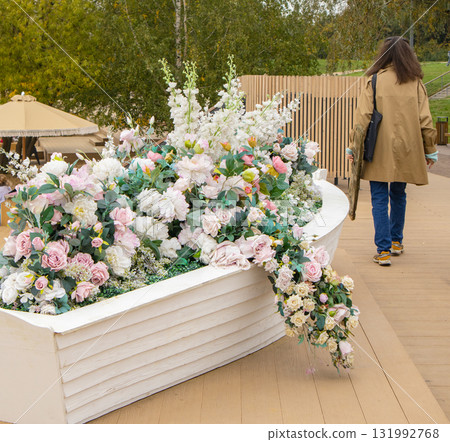 Flower boat with pastel roses and peonies on waterfront woman walking vertical composition Flower boat with pastel roses and peonies on waterfront woman walking vertical composition 131992768