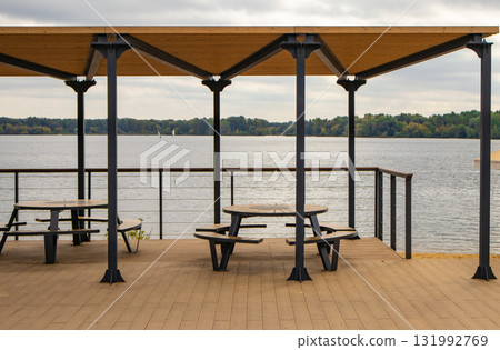 Waterfront terrace with round picnic table and canopy on a calm lake 131992769