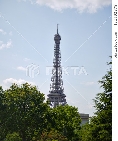 Eiffel Tower above green trees and blue sky in Paris 131992878
