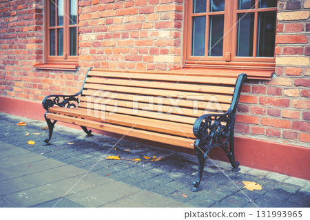 Wooden bench near an old brick building Wooden bench near an old brick building 131993965
