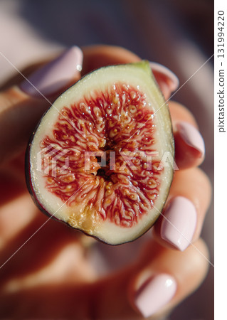 Freshly cut fig held in hand showcasing its vibrant inner texture 131994220