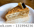 A delicious, close-up, high-angle shot of a single slice of Medovik, or honey cake, served on a round white porcelain plate 131994236