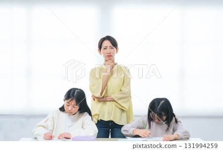 兩個正在學習的女孩身後一位憂心忡忡的女人 兩個正在學習的女孩身後一位憂心忡忡的女人 131994259