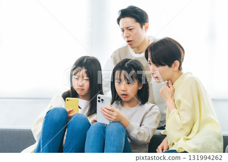Family of elementary school girl with troubled expression looking at smartphone 131994262